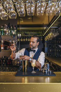 Bartender making drinks on counter in bar