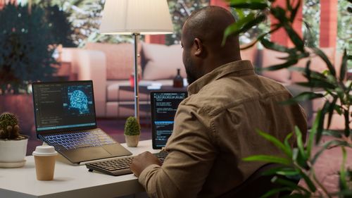Rear view of man using laptop on table