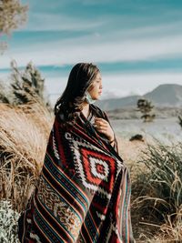 Woman wearing shawl looking away while standing on filed