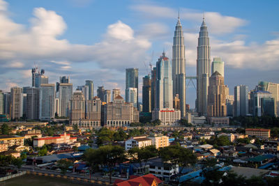 Petronas towers in city against cloudy sky