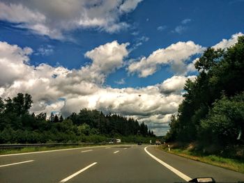 Road by trees against sky