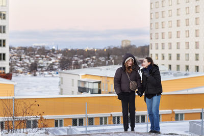 Female couple holding hands in modern neighborhood