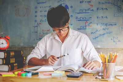 Man studying at desk against whiteboard