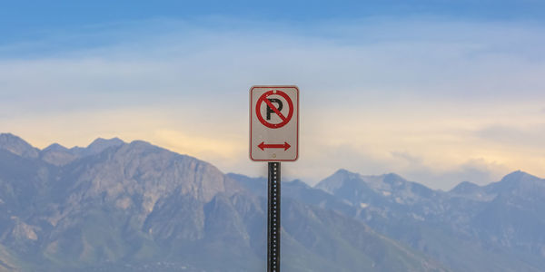 Information sign on snowcapped mountains against sky