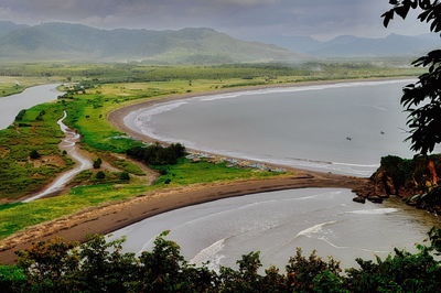 Scenic view of river by mountains against sky