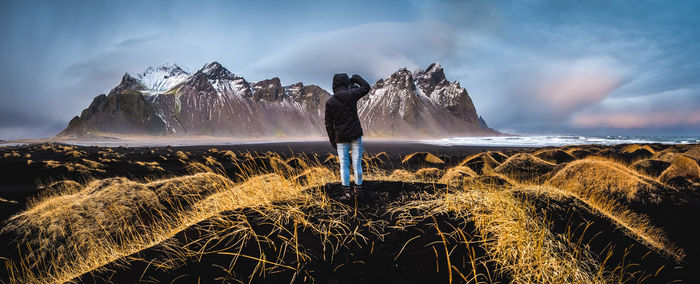 Scenic view of woman standing on a beach in front of mountains