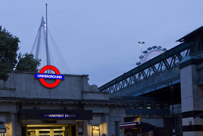 Low angle view of sign board bridge against sky in city