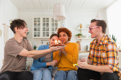 Friends using mobile phone while sitting at home