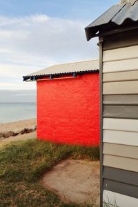 Cottage at beach against sky