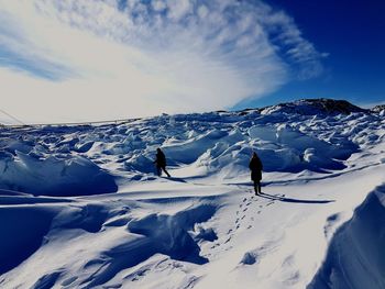 Person walking on snow covered mountain against sky