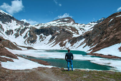 Rear view of man walking on snowcapped mountain