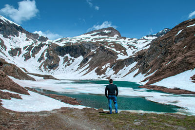 Rear view of man walking on snowcapped mountain