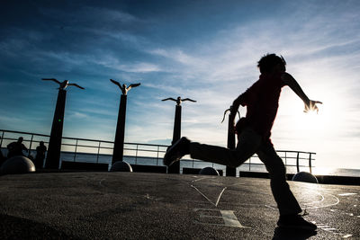 Full length of silhouette boy running on navigational compass against sky