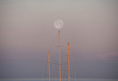 Masts of a sailboat under a mystic full moon