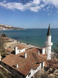 Buildings by sea against sky