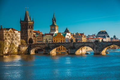 Bridge over river in city against blue sky
