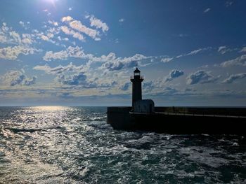 Lighthouse by sea against sky