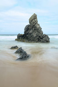 Rock formation on beach against sky