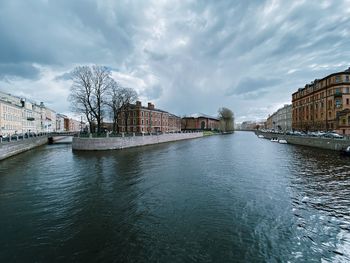 Buildings by river against sky