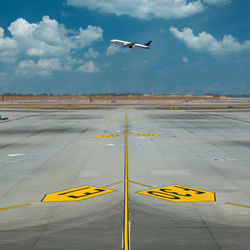 Airplane flying over runway against sky