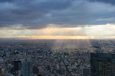 Aerial view of urban sprawl of tokyo, shinjuku district with sun rays penetrating dramatic sky