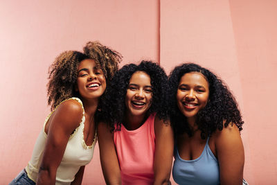 Portrait of smiling friends standing against wall