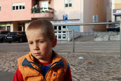 The blond boy sits on the street and is sad. six-year-old boy in a melancholy mood