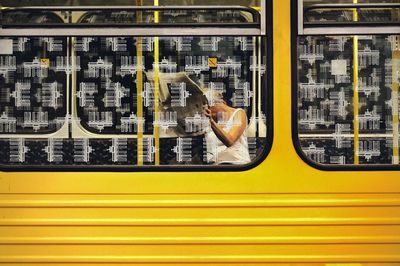 Woman reading newspaper in yellow train