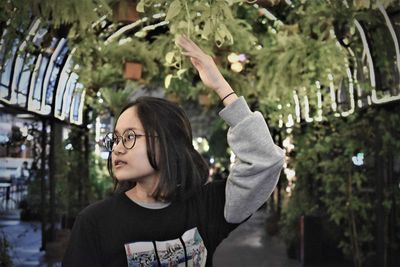Girl with hand raised standing against trees at night