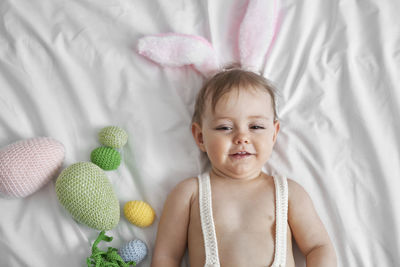 Portrait of cute baby girl lying on bed at home