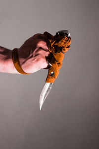 Close-up of hand holding weapon against gray background