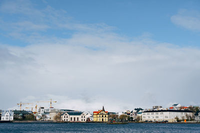 Buildings by sea against sky