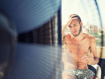 Shirtless man sitting outdoors