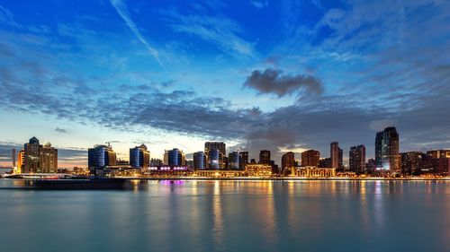 Illuminated buildings in city against sky