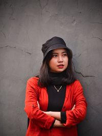 Portrait of young woman standing against wall