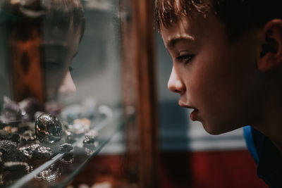 Close-up of boy looking at stones in cabinet