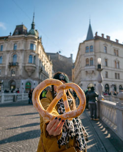 Front view of woman holding a pretzel. tourist in city of ljubljana, slovenia.