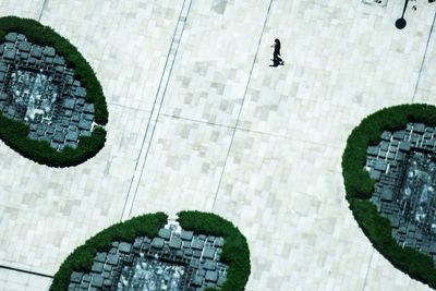 High angle view of woman walking on footpath with fountains in city