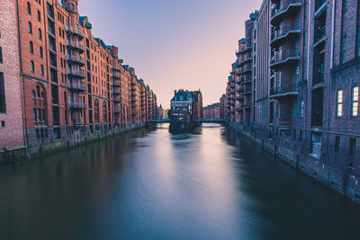 Canal amidst buildings in city against sky