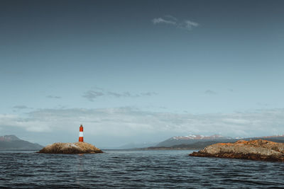 Lighthouse by sea against sky