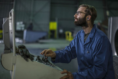 Worker operating machinery at control panel in factory