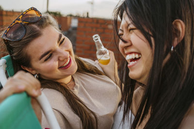 Happy woman wearing sunglasses looking at female friend laughing