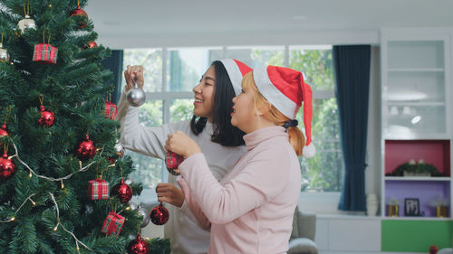 Midsection of woman standing by christmas tree