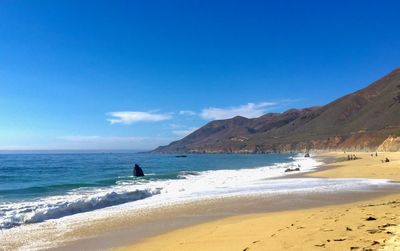 Scenic view of beach against blue sky