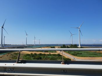Wind turbines on road against clear blue sky