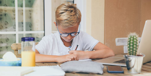 Student doing homework. boy writing, drawing sitting at the table. school, youth, education concept.