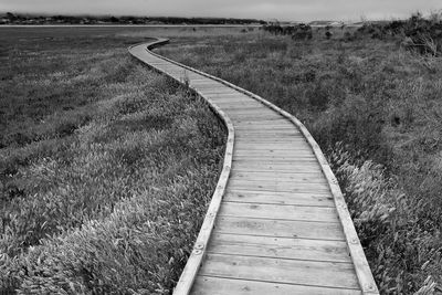 Boardwalk on field against sky