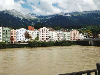 Buildings by river against cloudy sky