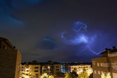 Lightning over illuminated cityscape against sky at night