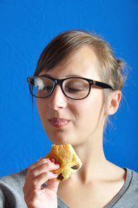 Woman eating food against blue background